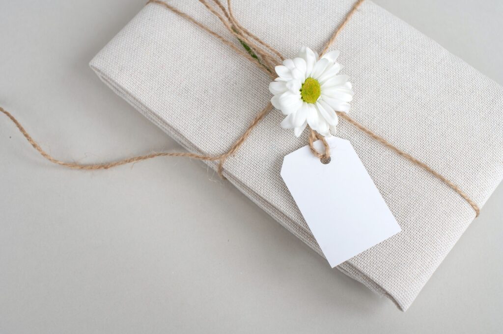 Empty price tag on white fabric, gift linen fabric with a tag on a white background with a flower