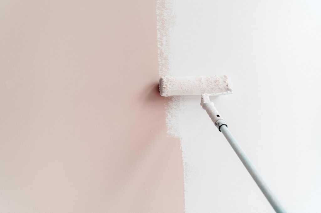 Painting house interior wall with roller into white. Apartment renovation, redecoration and repair
