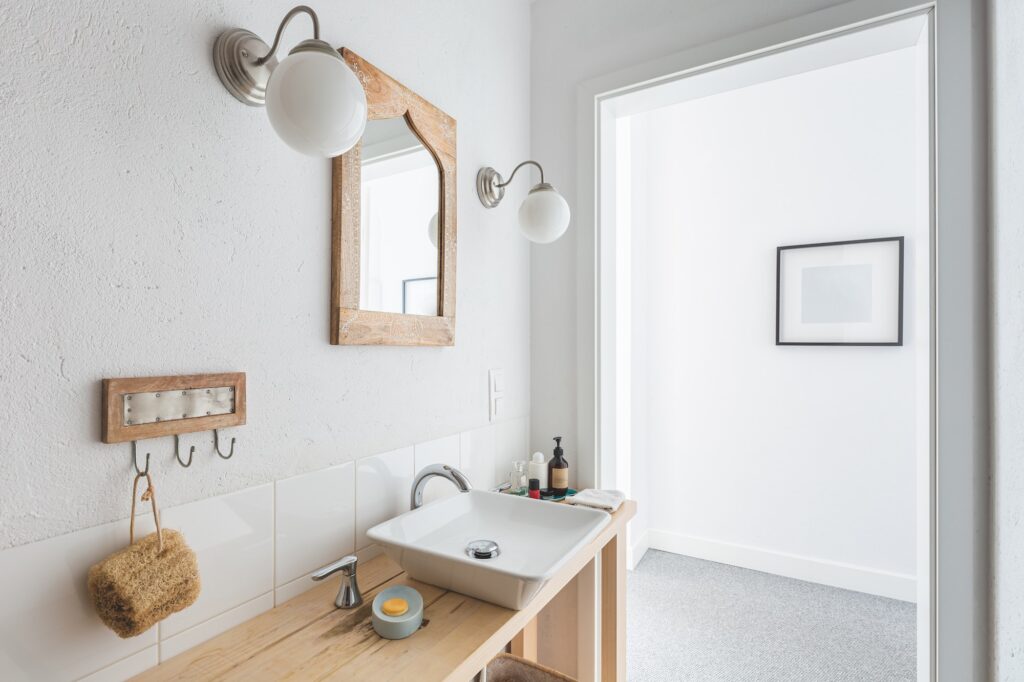 Stylish ceramic sink on trendy wooden console table in small elegant bathroom