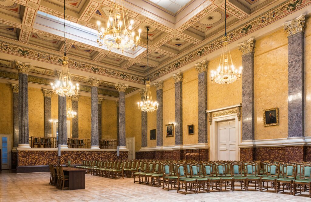 A large room with rows of chairs and chandeliers, part of the Museum of Fine Arts in Budapest