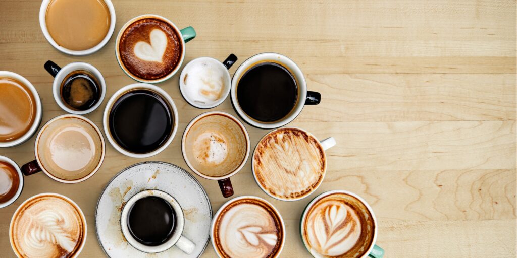 Assorted coffee cups on a light brown wooden board