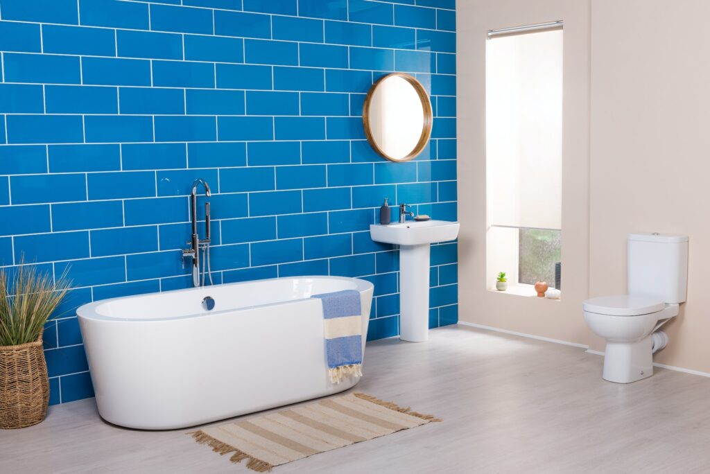 Beautiful shot of a radiant modern bathroom with tub, blue wall, window, and toilet