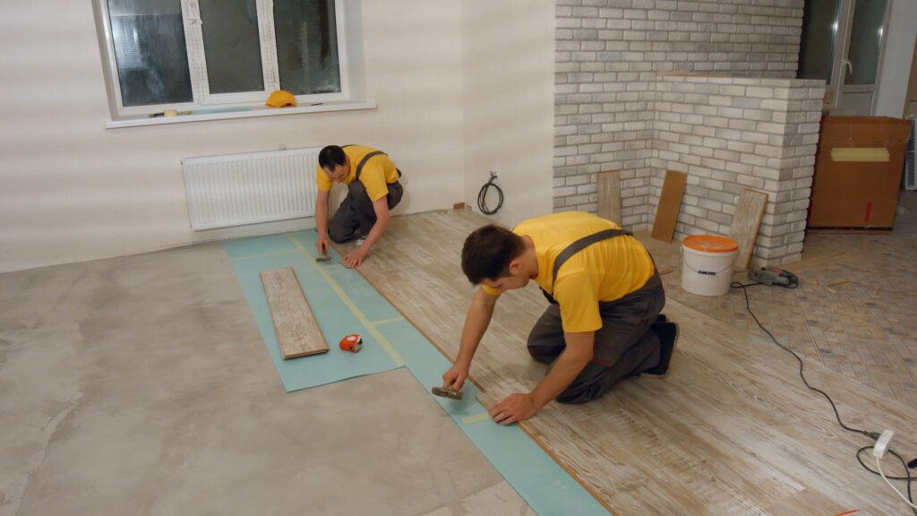 Builders installing laminate floor.