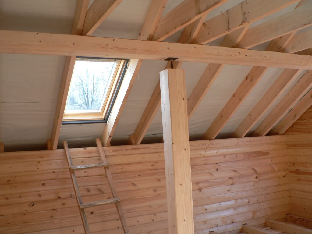 Construction of a wooden house, roof view with window.