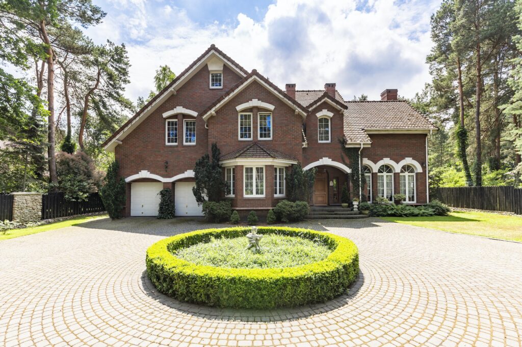 Front view of a driveway with a round garden and big, english st