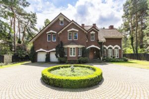 Front view of a driveway with a round garden and big, english st