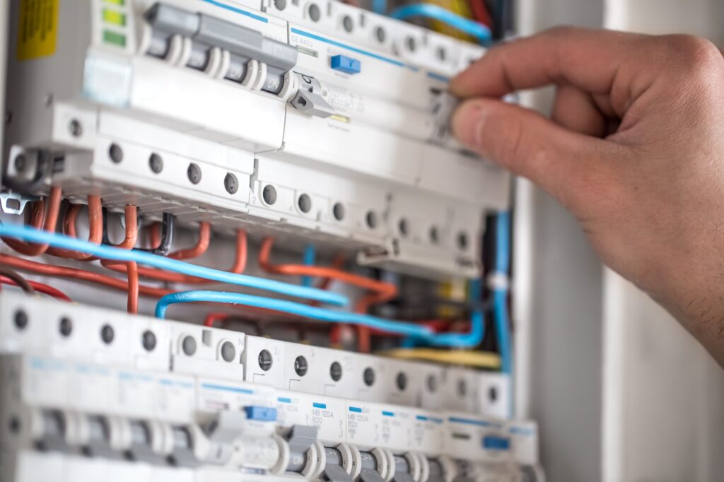 Man, an electrical technician working in a switchboard with fuses.