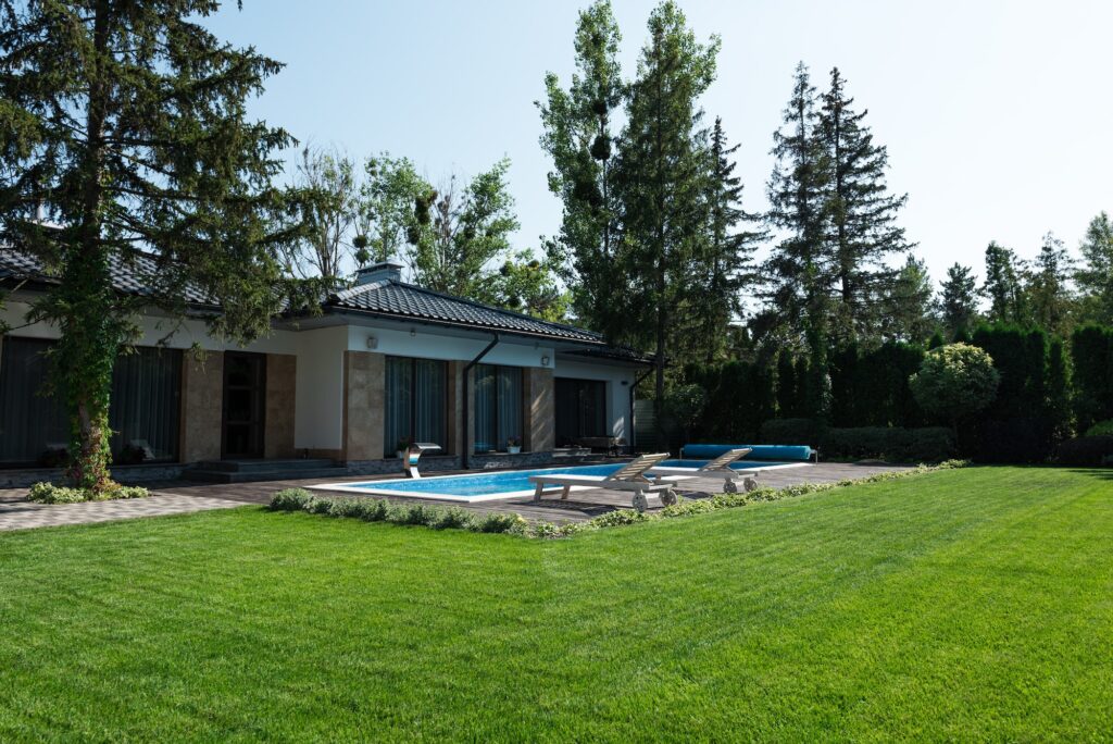 outside view of modern house, green lawn and poolside with sunbeds