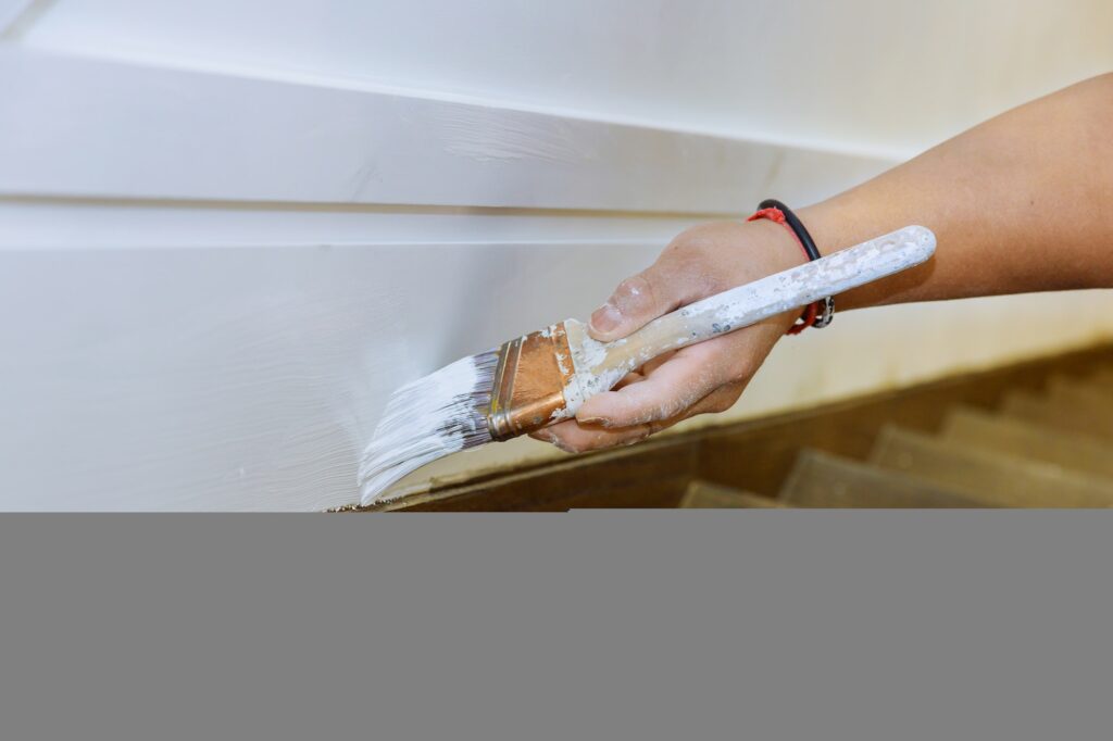 Professional painter cutting in with brush man is painting molding stairs flooring with brush