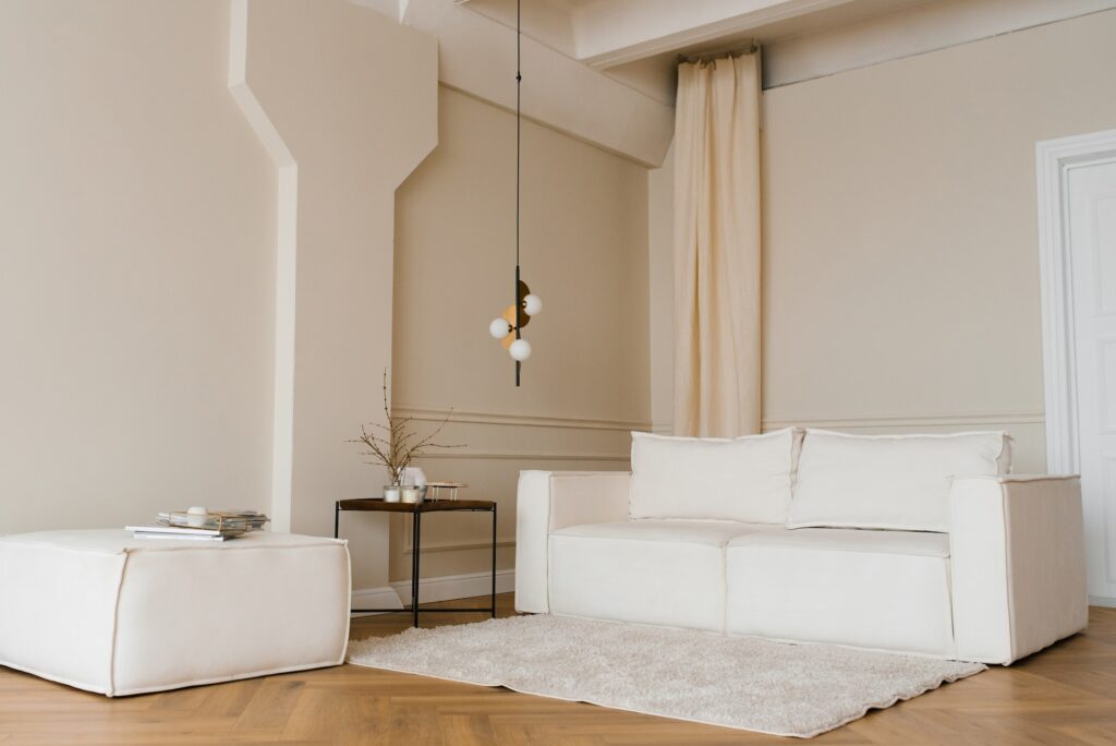 Scandinavian interior with a light sofa on wooden parquet floor, a wooden side table and beige walls