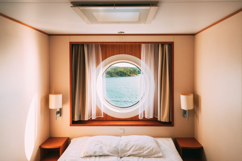 Ship Window In Craft Cabin With Bed. View On Sea. Luxury Cabin On Ferry Boat Or Cruise Liner. Sea