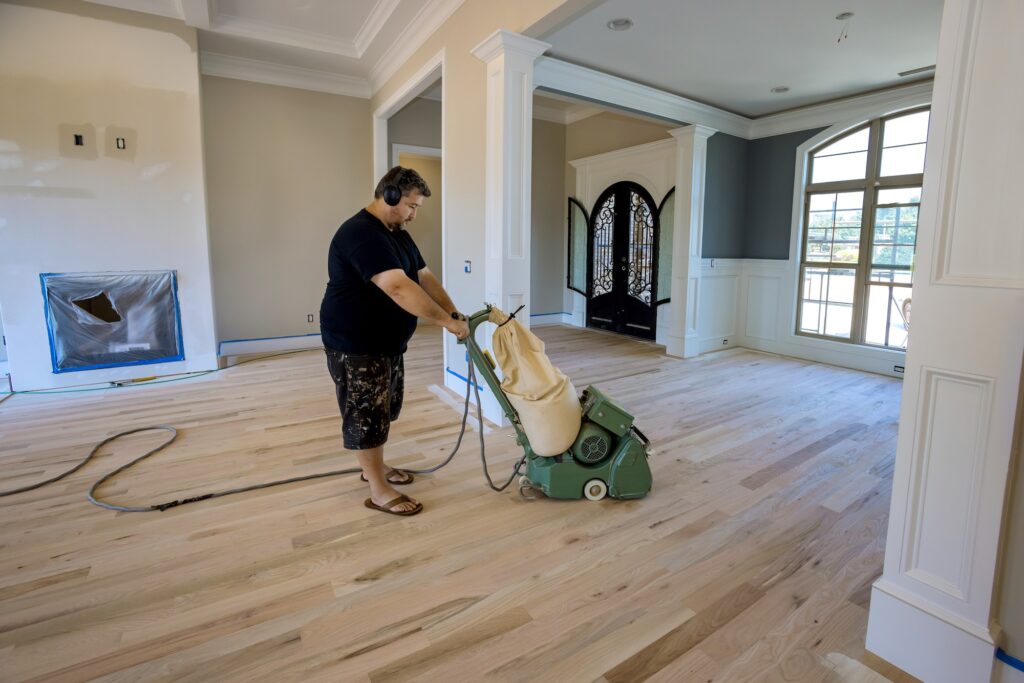 The process grinding a wooden parquet floor in using floor sander of newly constructed house