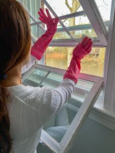 Woman cleaning home windows conveniently tilting & turning them to get them completely clean easily