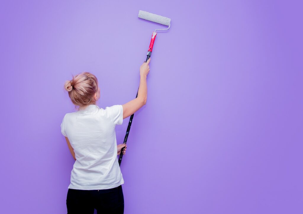 woman with paint roller in own house try to painting a room