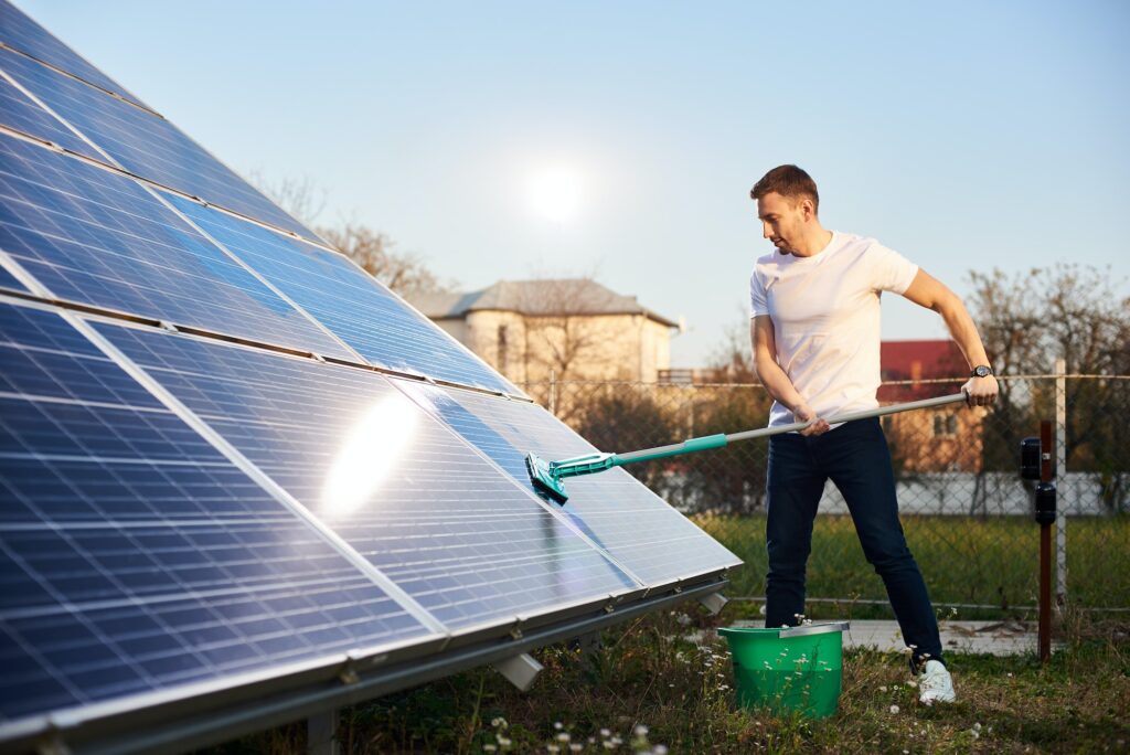 Young man cleaning solar panel