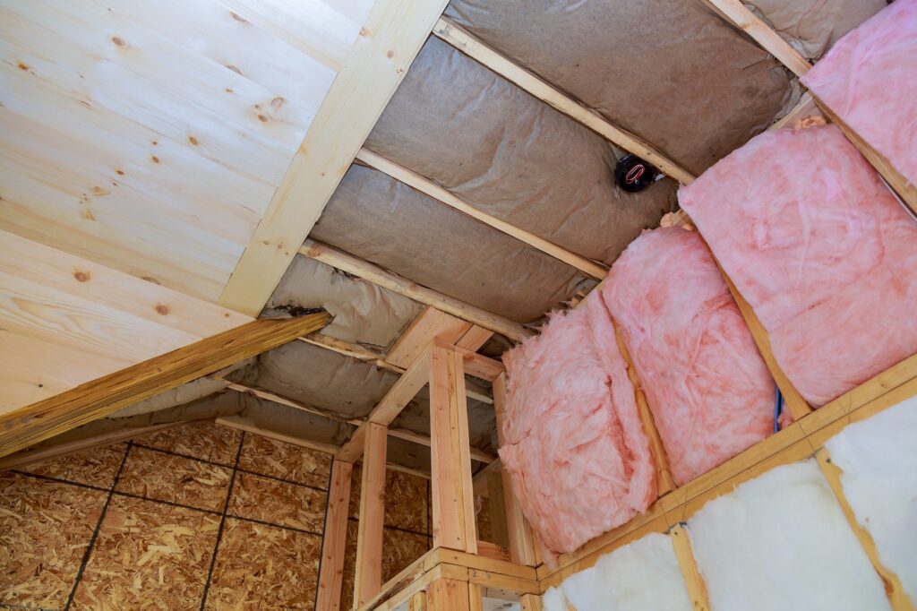 Attic loft insulation partly insulated wall covering view of layers of pink fiberglass barrier