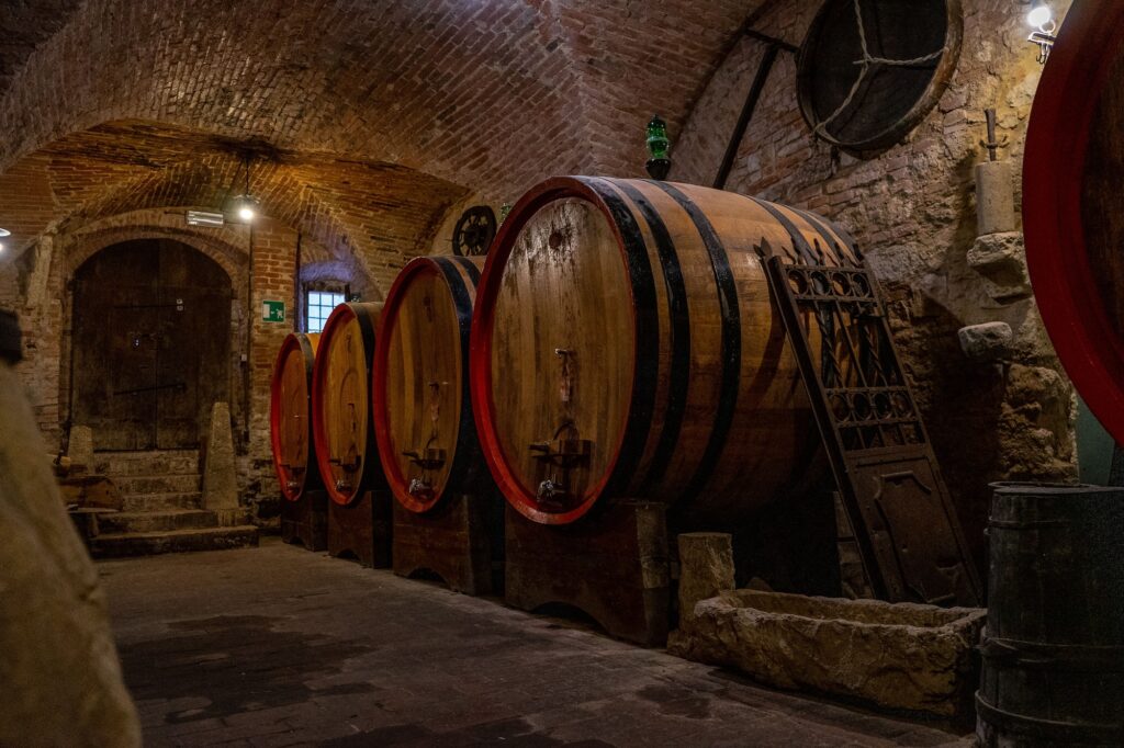 Closeup shot of oak barrels in a wine cellar with brick walls and an old wooden door