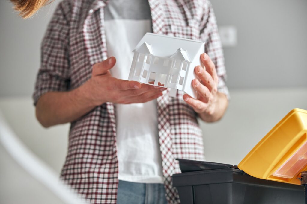 Experienced engineer studying a plastic miniature house