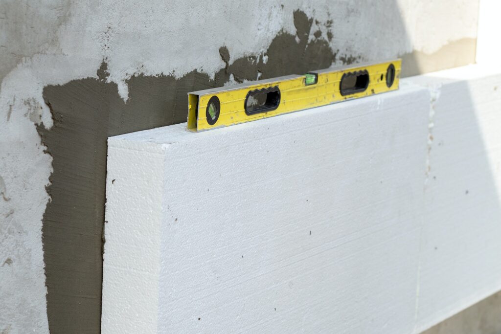 Insulation of facade wall with styrofoam sheets. Polystyrene insulation boards with glue adhesive.