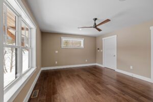 Large empty room with a ceiling fan and wood floors