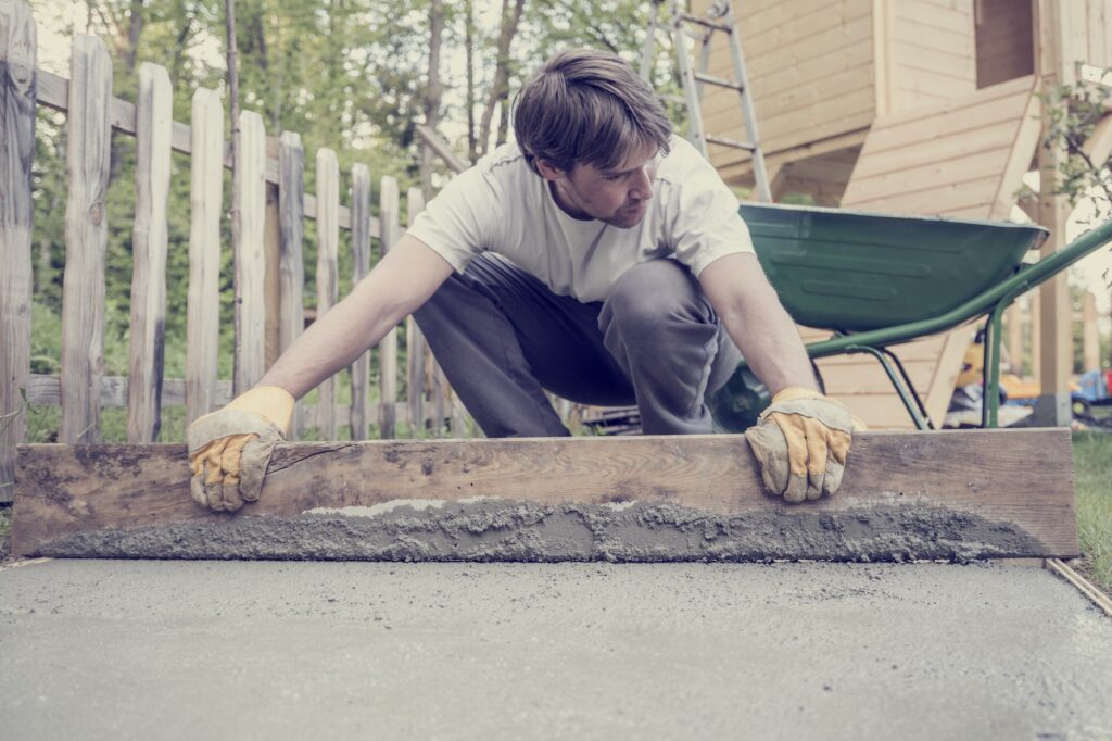 Man leveling the cement in a backyard