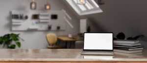 Modern marble tabletop with laptop mockup over blurred modern home workspace in attic room