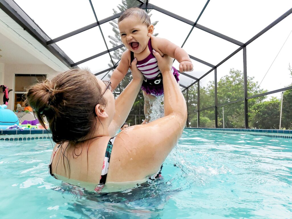 Mom and baby daughter having fun playing and keeping cool in their lanai enclosed Florida pool