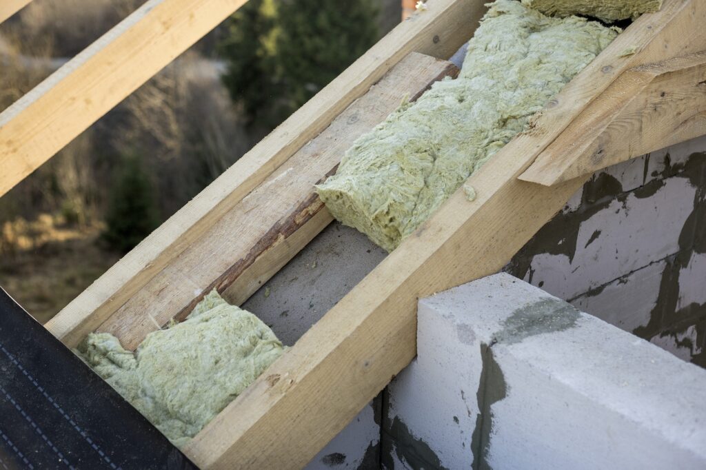 Roof construction and insulation with mineral wool. Wooden beams frame on walls of hollow foam