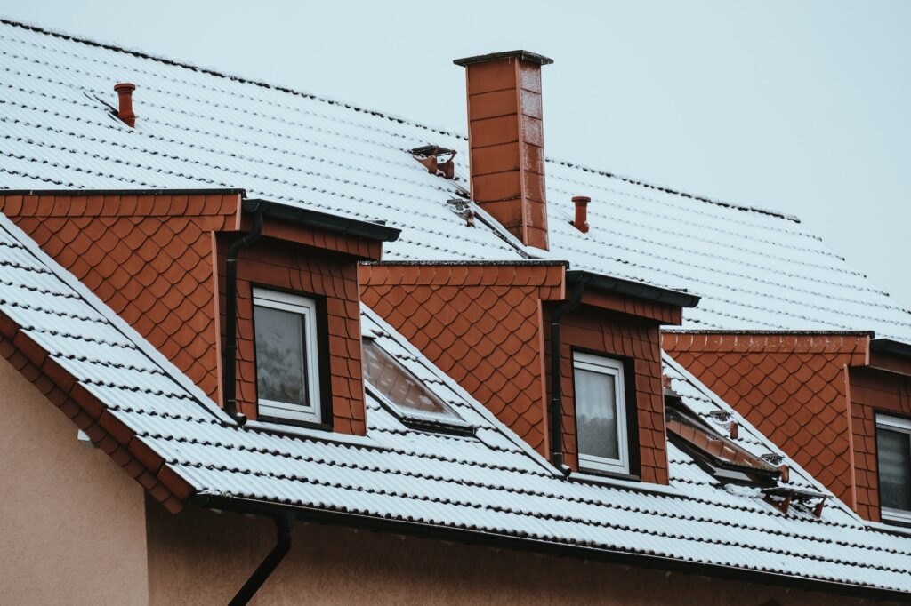 Roof of a house with many dormers covered by snow in winter