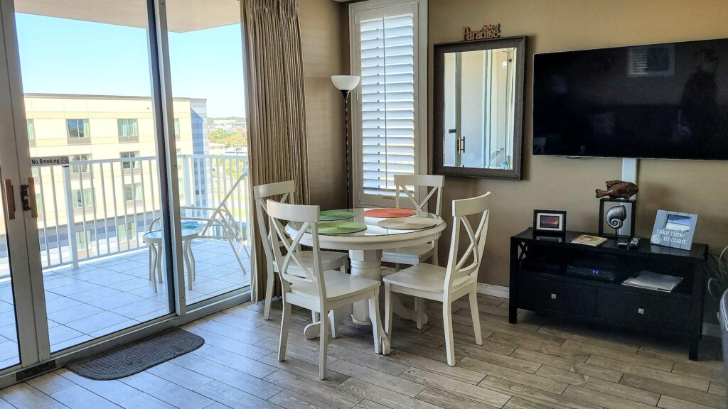 Small beach condo with dining room set in living room overlooking outdoor living space with bay view