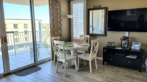 Small beach condo with dining room set in living room overlooking outdoor living space with bay view